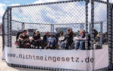 mehrere Personen in einem Käfig, auf dem Käfig befindet sich ein Banner mit
                  der Aufschrift: www.nichtmeingesetz.de