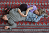 Bild 2: Charline Barboutie und Vincent Languille, zwei
Kinder die auf einem Teppich liegen. Bild in Farbe.