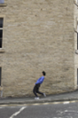 Bild 3: Brian Wakeling, läuft in schräger Haltung eine
Straße entlang. Bild in Farbe.