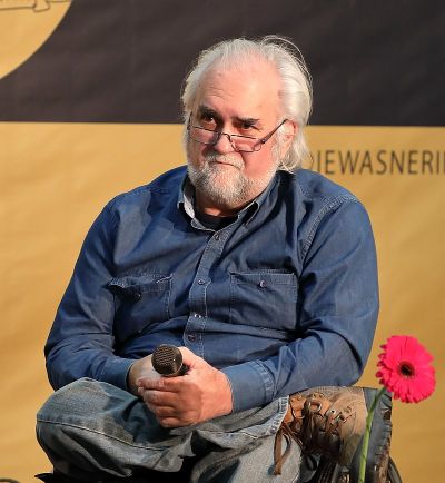 Erwin Riess bei der Wiener Buchmesse 2017 mit blauen Jeans-Hemd und einem Mikrofon in den Händen.